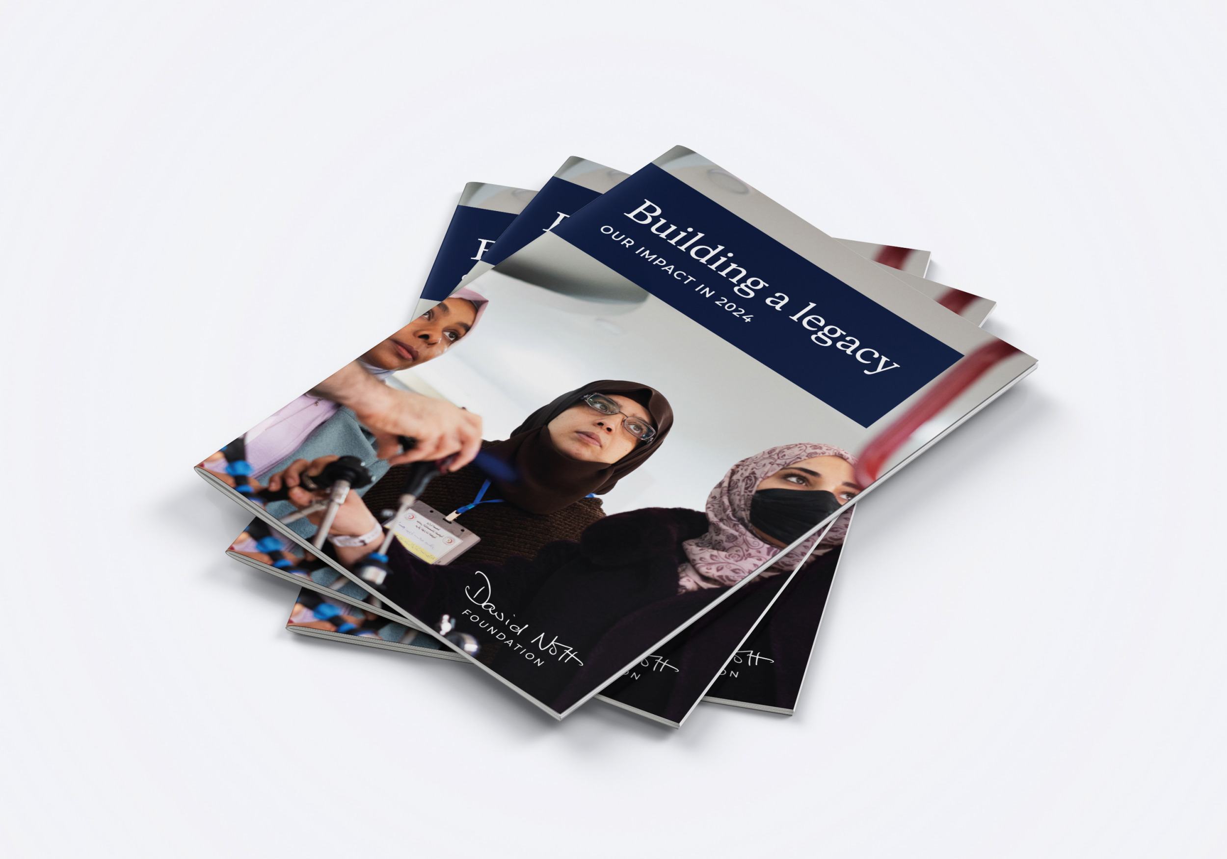 A stack of ‘Building a legacy: our impact in 2024’ reports, with a photo of women in hijabs at a surgical training session on the cover